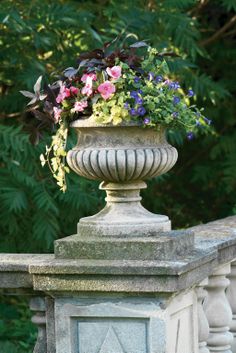 a planter filled with flowers sitting on top of a stone fence