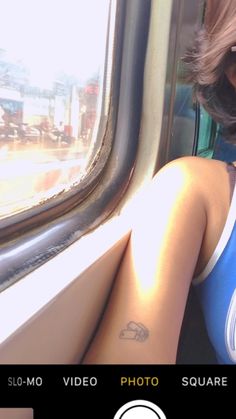 a woman sitting on a train looking out the window with her arm around her neck