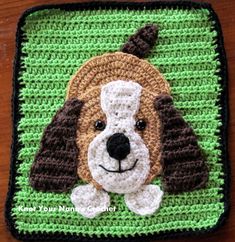 a crocheted dog with a hat on it's head is sitting in front of a green square