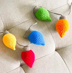 three crocheted christmas lights hanging on a white couch with grey cord attached to them