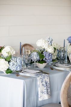 the table is set with blue and white floral centerpieces, silverware, and napkins