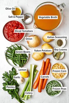 the ingredients for this vegetable soup are labeled in small bowls and on separate plates, including carrots, onions, celery, onion, green beans, garlic, lemon, parsley,