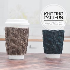 two knitted coffee cups sitting next to each other on top of a wooden table