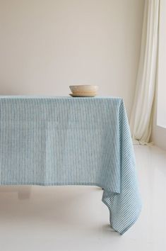 a bowl on top of a table next to a blue and white striped cloth draped over it