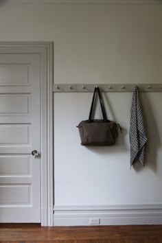 a coat rack with two coats hanging on it next to a white door and wooden floor