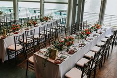 tables set up with white linens and orange flowers for an outdoor wedding reception at the water's edge