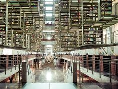 a large library filled with lots of books next to metal railings and stairs on both sides