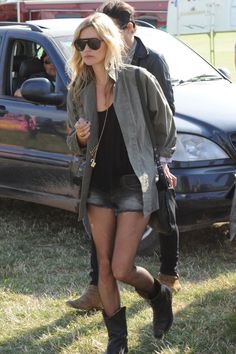 a woman in short shorts and boots walking next to a car