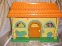 a toy house with an orange roof and flowers on it