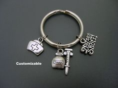 "Nurse Keychain / Nurses Call the Shots / Medical Assistant Keychain / Nursing Student Keychain / Nurse Key Ring / Gift for Nurse  All my keychain are customizable - if you want to add or exchange a charm, add a letter, number, or a birthstone, please contact me before placing your order. This keychain was handmade with nurse cap, syringe and \"nurses call the shots\" charms.   Your choice of - small key ring  - 1\" (2.5cm) diameter - large key ring - 1.2\" (3.2cm) diameter Add an initial charm  https://www.etsy.com/ca/listing/454708888/add-on-charm-add-a-personalized-initial?ref=shop_home_active_1 Check out my other keychains https://www.etsy.com/ca/shop/Trend4Ever?ref=hdr_shop_menu&section_id=7767364 Please contact me if you have any questions. Thank you for looking and have a great day! Personalized Silver Keychain For Personal Use, Personalized Silver Keychain, Silver Keychain With Lobster Clasp, Large Key Rings, Nurse Keychain, Nurse Cap, Nursing Cap, Gift For Nurse, Medical Assistant