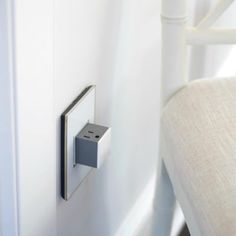 an electronic device mounted to the side of a white wall next to a pillow on a bed