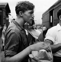 black and white photograph of people walking down the street talking on their cell phones while holding paper bags