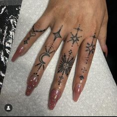 a woman's hand with stars and moon tattoos on her left hand, while the other hand has a star tattoo on it