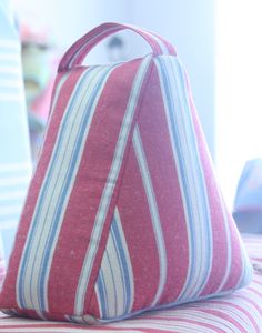 a red and blue striped pillow sitting on top of a bed