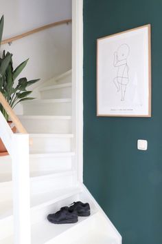 a pair of black shoes sitting on the ground in front of a green painted wall