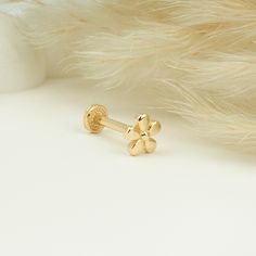 a pair of gold earrings sitting on top of a white surface