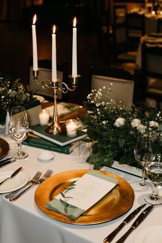 the table is set with place settings, silverware, and candles for an elegant dinner