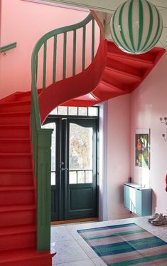 there is a spiral staircase in the room with pink walls and red carpet on the floor