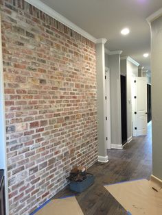 a brick wall is being installed in an empty room with hard wood flooring on the ground