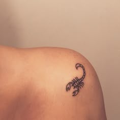 a scorpion tattoo on the back of a woman's shoulder