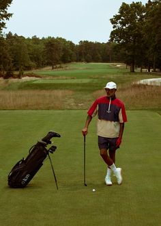 a man standing next to a golf bag on top of a green