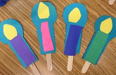 four popsicles made out of construction paper on a wooden table with scissors in the background