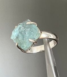 Offered here is stunning rough cut blue aquamarine ring. This aqua beauty catches the light and looks like a frozen blue ice crystal! This natural aquamarine is set in a sterling silver band. The stone measures approx 11.6 mm long x 11.2 mm across x 7.9 mm tall.  This ring weighs 5.2 grams and is approx size 7.5.  The ring is marked 925. Frozen Blue, Rough Stone Ring, Blue Aquamarine Ring, Raw Aquamarine, Blue Ice, Aquamarine Ring, Aquamarine Rings, Aquamarine Blue, Natural Aquamarine