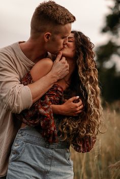 a man and woman kissing in the middle of a field