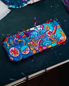 a cell phone case sitting on top of a table covered in colorful art paint and confetti