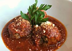 meatballs covered in sauce and garnished with parmesan cheese on a white plate