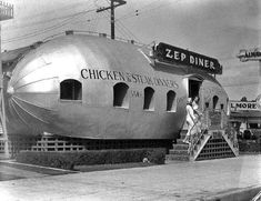 a large silver boat sitting on top of a sidewalk next to a building and stairs