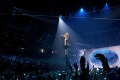 a person standing on top of a pole in the middle of a crowd at a concert