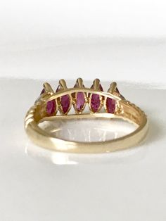 Surprise her with this vintage ruby yellow gold ring in 14k. The sparkling design of this July birthstone ring has 5 Marquise shaped real rubies with 2 tiny diamonds on a scalloped band. The genuine ruby ring is full of character with the scalloped band and, crescent moons on the sides. This luscious ruby ring with its gorgeous pinky red color is a classic timeless piece, and would make a great anniversary present. The size 7 ring is in excellent condition! Rubies are the gemstone for the 15th w Marquise Ruby Ring In Yellow Gold, Marquise Ruby Ring With Prong Setting, Ruby Birthstone Ring Marquise Cut For Anniversary, Ruby Marquise Cut Birthstone Ring For Anniversary, Fine Jewelry Marquise Cut Ruby Ring In Yellow Gold, Marquise Ruby Ring In Gold, Marquise Cut Ruby Birthstone Ring For Anniversary, Marquise Ruby Ring As Birthstone, Anniversary Ruby Birthstone Ring With Marquise Cut