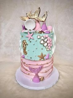 a multi layer cake decorated with mermaid decorations