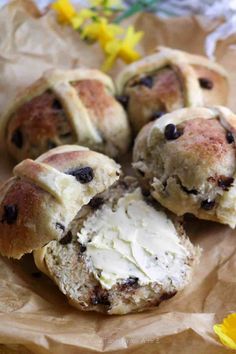 several rolls with cream cheese and chocolate chips on them sitting on wax paper next to yellow flowers