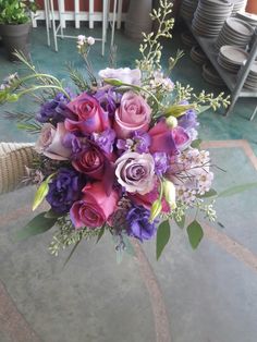 a bouquet of purple and pink flowers sitting on top of a table next to plates