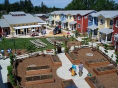 an aerial view of several colorful houses and gardens with people walking around the garden area