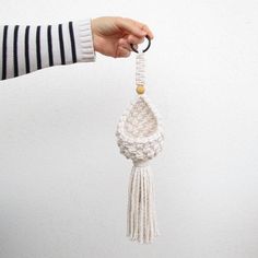 a person is holding a white macrame ornament in their left hand