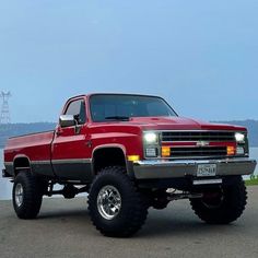 a red pick up truck parked next to the water