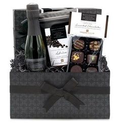 a bottle of wine and chocolates in a black box with a bow on it