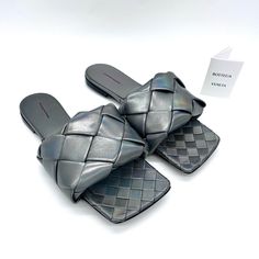 Grey ‘Lido’ Slides From Bottega Veneta. Crafted From Lamb Leather With A Shimmering Holographical Effect, This Model Showcases The Brand's Signature ‘Intreccio’ Weave, A Square Toe And A Beige Leather Sole With Anti-Skidding Rubber Inserts To Ensure Stability. Outer And Inner Layer: 100% Lamb Leather Sole: Leather Rubber, Sole Height: 1cm Sole Height At The Highest Point: 2cm. Made In Italy Designer Woven Leather Evening Sandals, Luxury Evening Sandals With Intrecciato Weave, Luxury Intrecciato Weave Evening Sandals, Designer Sandals With Intrecciato Weave For Summer, Luxury Sandals With Intrecciato Weave And Round Toe, Bottega Veneta Shoes, Flat Sandals, Bottega Veneta, Women's Shoes Sandals