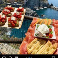 some food is laying out on a table near the ocean and mountains in italy,