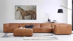 a living room with a couch, ottoman and painting on the wall