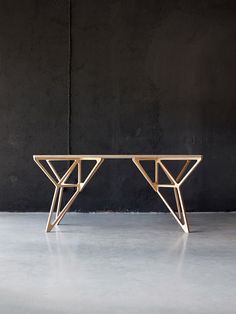 a wooden table sitting on top of a cement floor next to a black brick wall