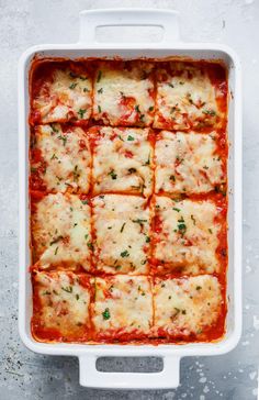 a white casserole dish filled with meat and cheese covered in marinara sauce