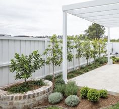 an outdoor patio area with stone steps and plants in the foreground, surrounded by white fence