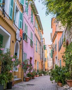 a woman is walking down the street in front of some buildings with green shutters