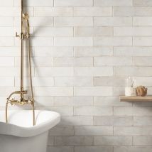 a white bath tub sitting next to a shelf filled with soap and toothbrushes