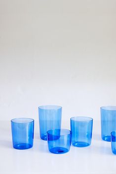 five blue glass cups sitting next to each other