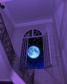 the moon is seen through an open window in a building with wrought iron railings